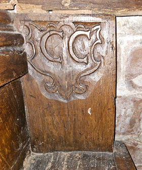 17th-century pews, one bearing the letters  C C on a shield